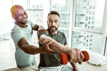 Positive delighted international therapist helping his client