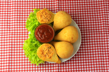 Coxinha in the dish, traditional Brazilian cuisine snacks stuffed with chicken, on rustic wooden table
