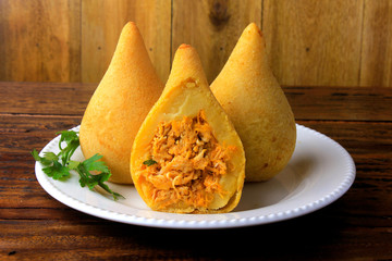 Coxinha in the dish, traditional Brazilian cuisine snacks stuffed with chicken, on rustic wooden table