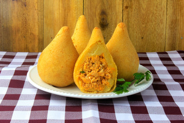 Coxinha in the dish, traditional Brazilian cuisine snacks stuffed with chicken, on rustic wooden table