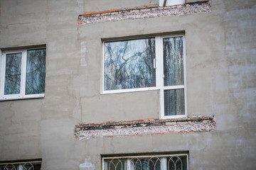 Broken concrete balcony on the facade of the building. Restoration of an old residential gray...