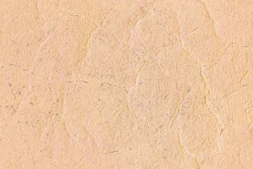 Seamless texture of a concrete wall. Cracks and irregularities on a light yellow-pink plaster. Abstract background.