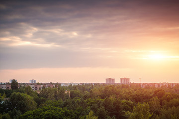 Fototapeta premium Abandoned uninhabited city overgrown with trees and bushes. Dark region of the radioactive town in the evening. Houses in the woods at sunset.