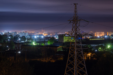 Power line against the background of factories of enterprises of the night city.
