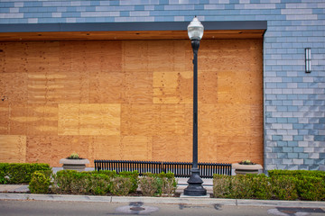 Plywood shutters prevent unauthorized access by squatters, looters or vandals to unused, vacant, or abandoned property. Economic recession concept - bankrupt business boarded up with plywood sheets