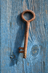 Old handmade metal key hanging on wooden wall