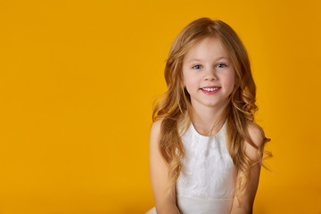 Portrait of cheerful smiling little cute little girl on yellow background isolated