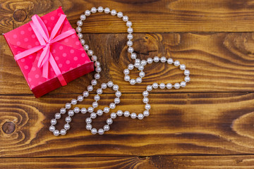 Obraz na płótnie Canvas Gift box and pearl necklace on wooden background