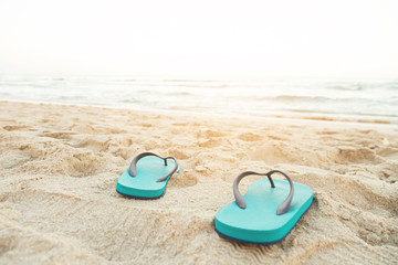 slipper of foot in sandals shoes and Blue ocean wave water distribution on sandy white beach, Sea background.The color of the water and beautifully bright. travel nature holiday summer concept.