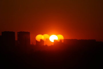 Spring sunrise in the city with optical illusion of multiple sun
