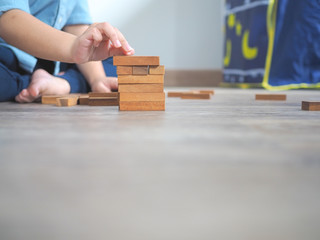 Small kid playing with wooden blocks on the floor
