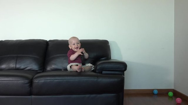 Happy smiling toddler boy watching tv with remote control in hands