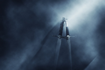 mysterious and magical photo of silver sword over gothic black background with smoke. Medieval...