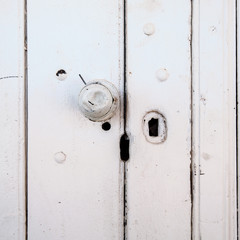 Dented door knob on an old painted wooden door