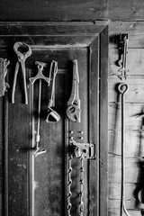 Black and white photo of old tools hung on a door