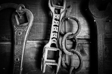 Black and white of old farm tools on wall.