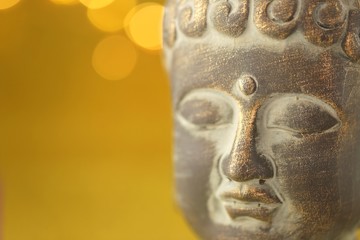 Buddha's head on golden background with golden bokeh.Close up on the head of Buddha statue .The face of Buddha