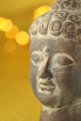 Buddha's head on golden background with  bokeh.Close up on the head of Buddha statue .The face of Buddha
