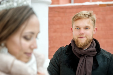 The groom looks at the bride and smiles on a winter day close-up. Winter wedding.