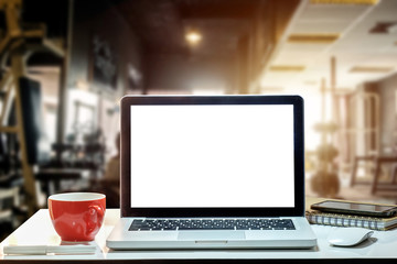 Front view of cup and laptop, smartphone, and tablet on table in Office in fitness gym in morning light
