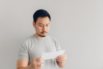 Man is reading the white mail message or the bill.