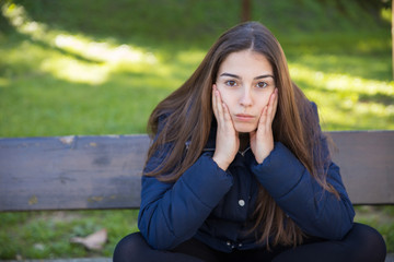 Pensive pretty woman posing at camera in park