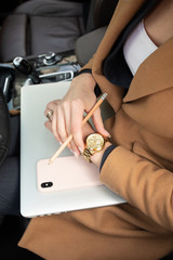 Young woman holding a phone. Workplace in car with laptop. Close up 