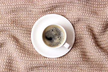  Cup of coffee on the background of a knitted plaid top view.