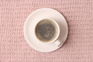  Cup of coffee on the background of a knitted plaid top view.