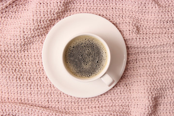  Cup of coffee on the background of a knitted plaid top view.
