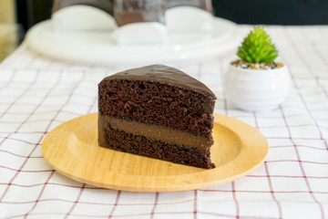 Piece of delicious chocolate cake on wooden plate