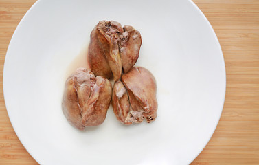 Boiled chicken liver in white plate on wooden board background.
