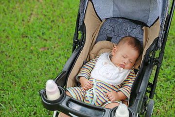 Fototapeta na wymiar Asian baby boy sleeping in stroller on nature park.