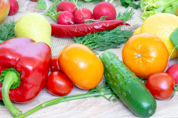 Vegetables and fruits closeup on wooden background. Mango, radish, yellow pepper, red pepper, lemon, cucumber, dill, tangerine, parsley.