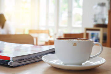 Cup of Hot  Latte Coffee on wood table with light window.