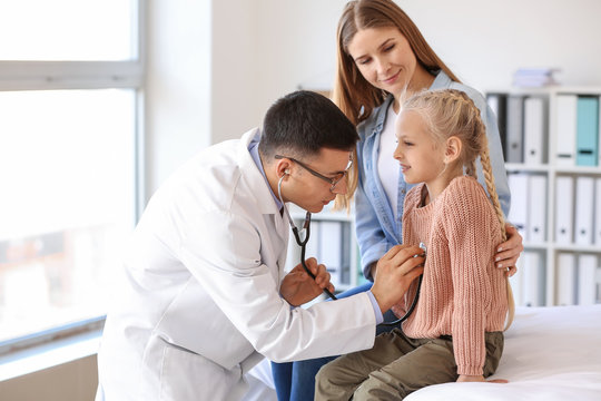 Pediatrician examining little girl in clinic