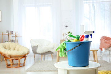 Bucket with cleaning supplies on table at home