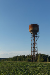 Water tower, sunlight and against a cloudy sky at dusk.