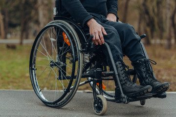 Obraz premium Close-up of male hand on wheel of wheelchair during walk in park