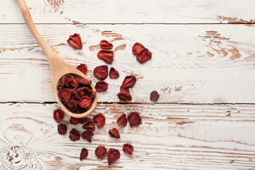 Spoon with tasty dried strawberry on white wooden background