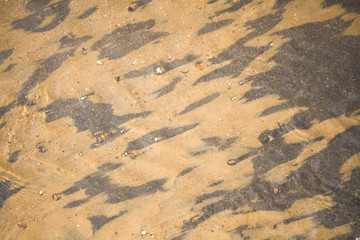 River sand. Texture of sand under water. Yellow fine sand and water texture. The best background for tourism. Sand under water on a black background. Clean and fresh spring water.