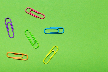 minimal office concept, six multi-colored clips laid out on a green background