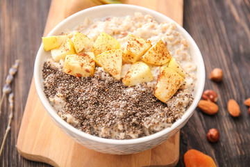 Bowl with tasty sweet oatmeal on wooden table