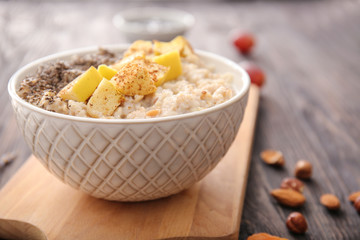 Bowl with tasty sweet oatmeal on wooden table