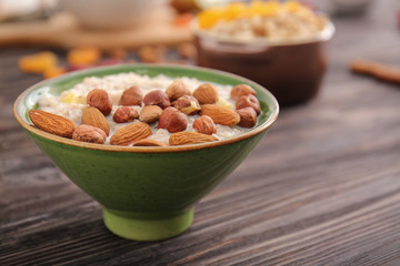 Bowl with tasty sweet oatmeal on wooden table