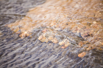 Background water. Asphalt and sand. Stream of water over the asphalt. Beautiful sea background with sand. Fine sand under water. Water texture Waves on the water. Different wavelength. The laws of phy