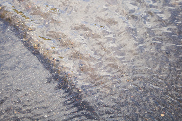Background water. Asphalt and sand. Stream of water over the asphalt. Beautiful sea background with...