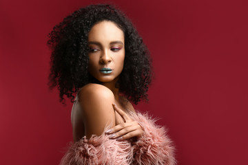 Portrait of beautiful African-American woman with unusual makeup on color background