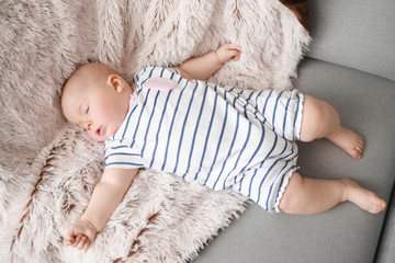 Adorable baby girl sleeping on soft sofa