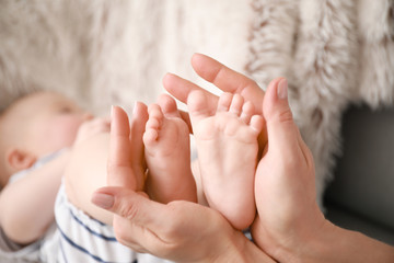 Mother's hands holding tiny feet of little baby, closeup